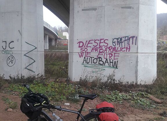 Am Autobahnpfeiler steht: "Dieses Graffiti - so erbärmlich wie eure Autobahn"